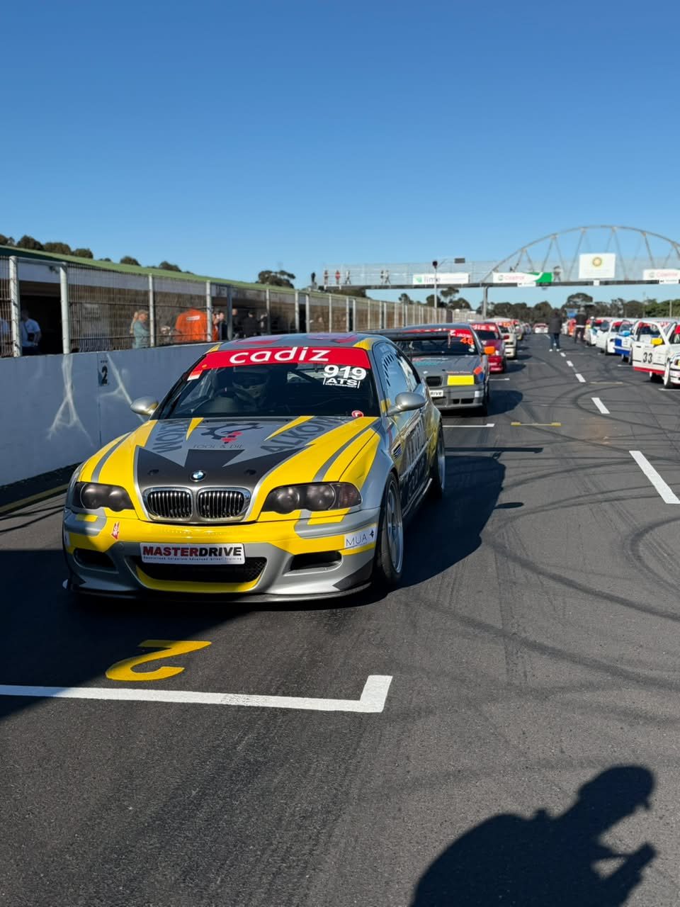 Number 919 · Yellow-and-silver BMW E46 in the grid lineup