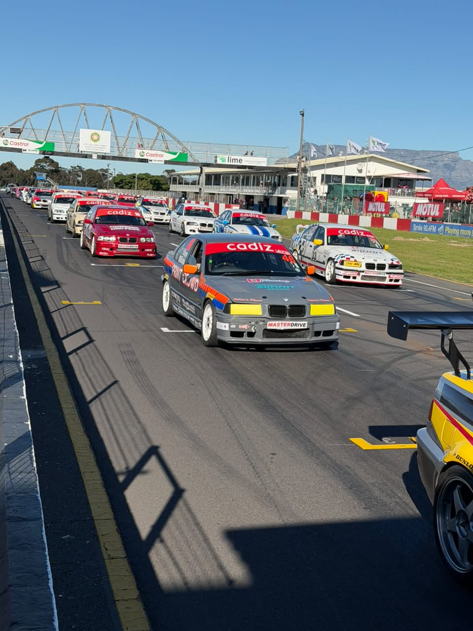 Number 46 · Grey-and-orange BMW E36 in the grid lineup